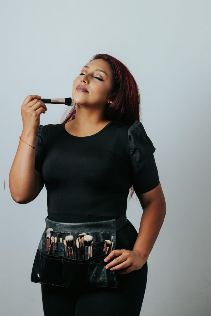 pexels-photo-26616194-26616194 Portrait of a female makeup artist holding a brush, showcasing her tools in a studio setting.