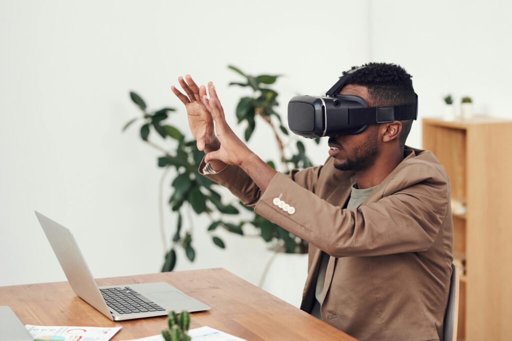 Man using a VR headset in an office with a laptop, engaging with virtual content.